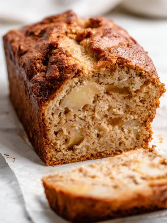 Ultra close-up of stacked slices of cinnamon apple bread showing caramelized crust and baked apple chunks