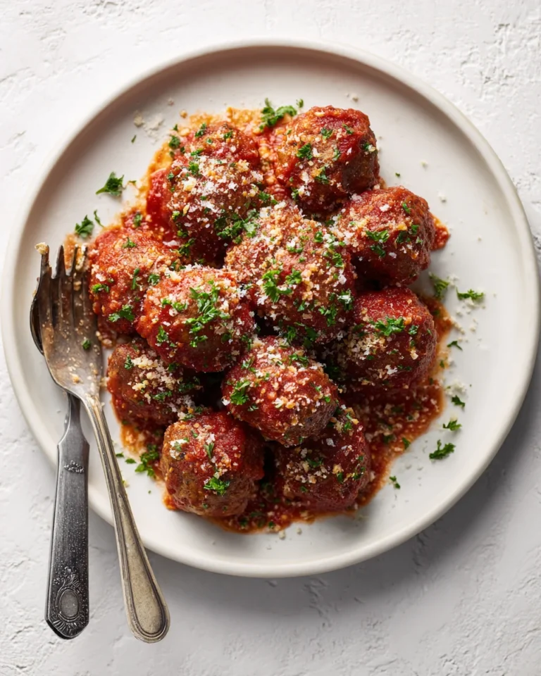 Plate of ricotta meatballs with sauce, parsley, and silver utensils