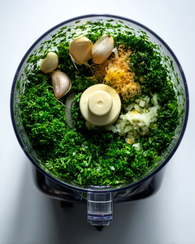 Parsley, garlic, lemon zest, and onion in food processor bowl before blending for tahini dressing