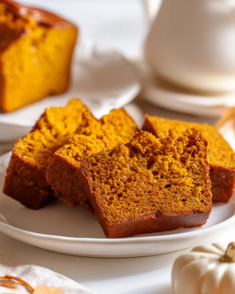 Pumpkin bread slices on a white plate showing moist golden crumb in bright natural light